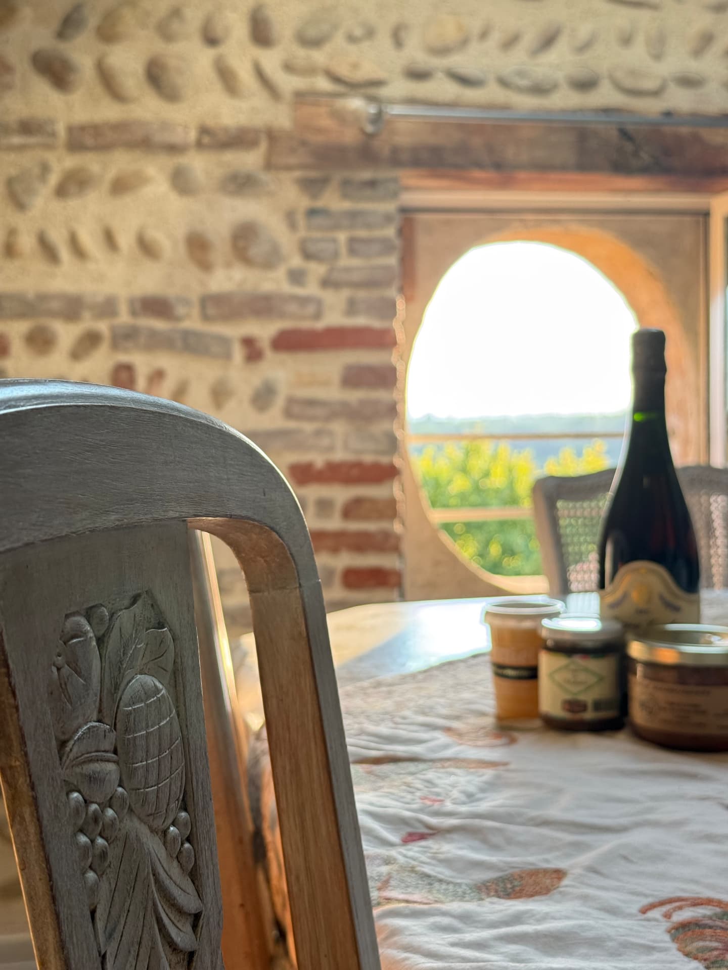 Table dressée avec produits locaux devant une fenêtre ronde en pierre