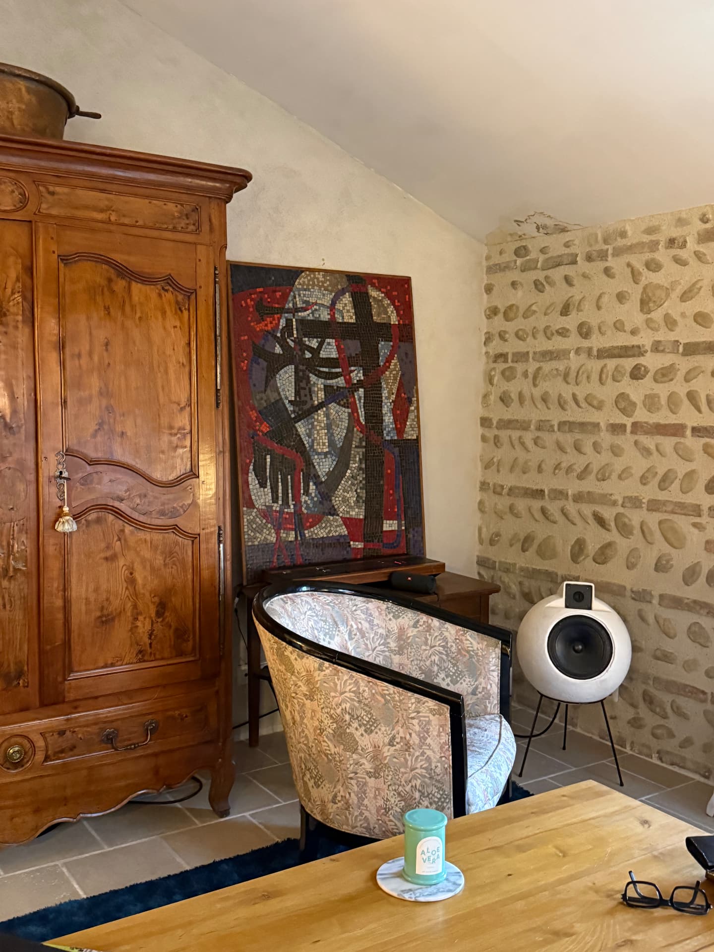 Séjour avec armoire ancienne en bois, mosaïque murale et mur de galets